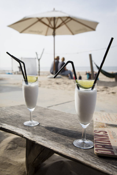 Cocktail glass with two straws and with beach landscape background - Photo, Image