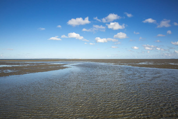 Maritiem landschap met blauwe hemel witte wolken en patroon in het zand, Waddenzee-Wadden Sea, Friesland, Nederland - Foto, afbeelding