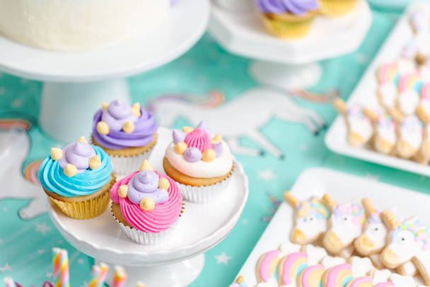Little girl birthday party table with unicorn cake, cupcakes, and sugaer cookies. - Foto, immagini