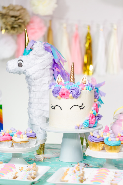 Mesa de fiesta de cumpleaños de niña pequeña con pastel de unicornio, cupcakes y galletas sugaer
. - Foto, imagen