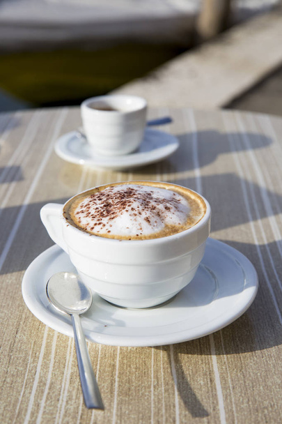 Cappuccino italiano fresco en una mesa de terraza cafetería
 - Foto, imagen