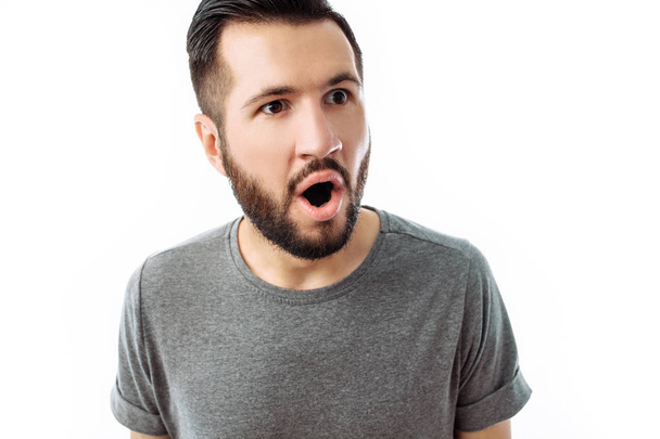 Portrait of cheerful and surprised man with beard, in grey t-shirt, looking at camera, isolated on white background, advertisement, text insertion - 写真・画像