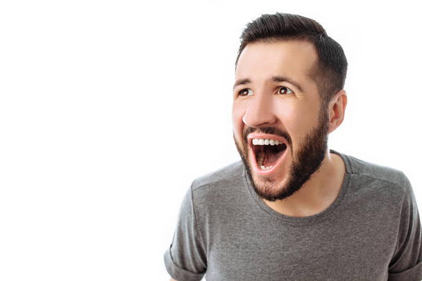 Retrato de hombre alegre y sorprendido con barba, en camiseta gris, mirando a la cámara, aislado sobre fondo blanco, publicidad, inserción de texto
 - Foto, imagen