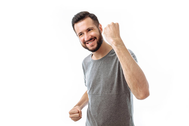Счастливый молодой хипстер в серой рубашке показывает эмоции счастья и радости, человек на белом фоне
 - Фото, изображение