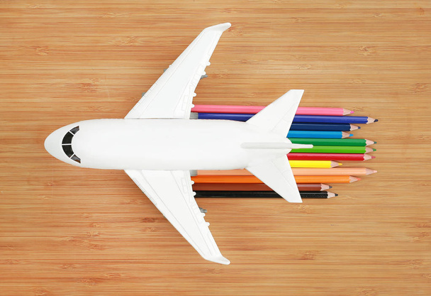 Airplane model on wooden background with colored pencil to concept speed of jet aircraft. - Φωτογραφία, εικόνα
