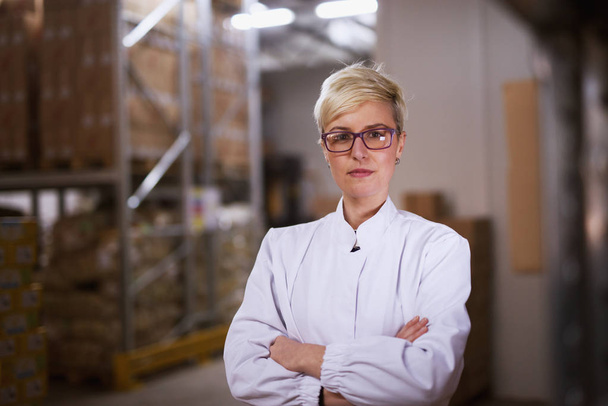  jovem trabalhador feminino profissional feliz em roupas estéreis brancas na sala de armazenamento de fábrica
 - Foto, Imagem