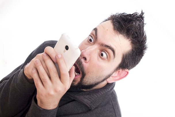 amazed Caucasian man holding mobile phone and staring at screen with opened mouth  - Fotó, kép