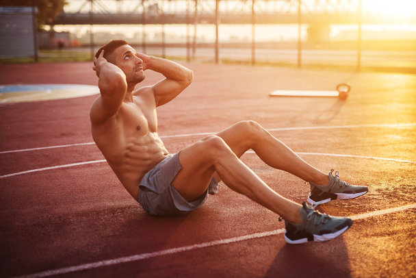 Fitness trénink venku. Pohledný muž pracující cvičení v brzy ráno s východem slunce. Svalnatý muž trénink venku. Fitness Slunečné ráno. - Fotografie, Obrázek