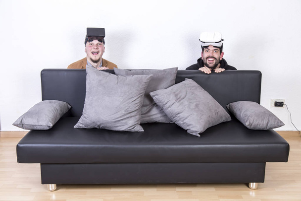two men in VR glasses behind sofa  - 写真・画像