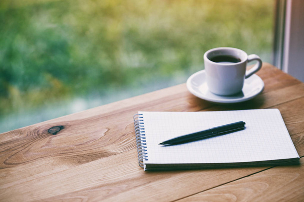cup of fresh morning coffee with paper notebook and pen for writing - Valokuva, kuva