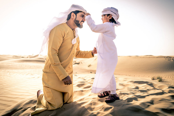 Happy family playing in the desert of Dubai -  Playful father and his son having fun outdoors - Foto, afbeelding