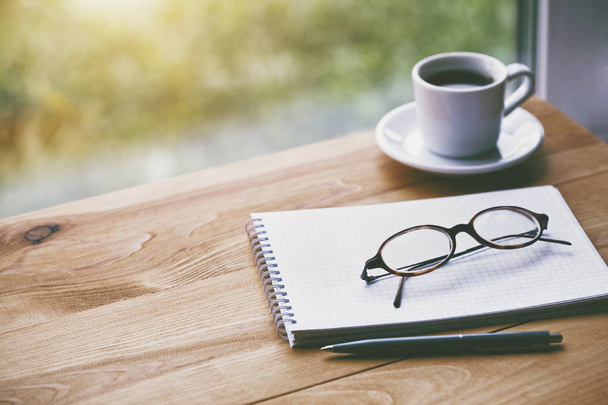 cup of fresh morning coffee with paper notebook, glasses and pen for writing - Foto, Imagen