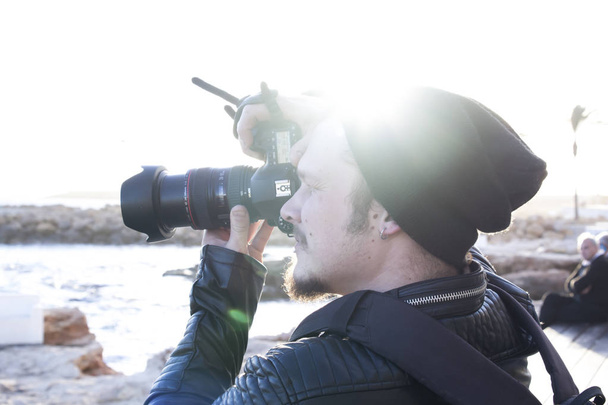 デジタル カメラ製造で若い男は昼間市内堤防上のキャプチャします。 - 写真・画像