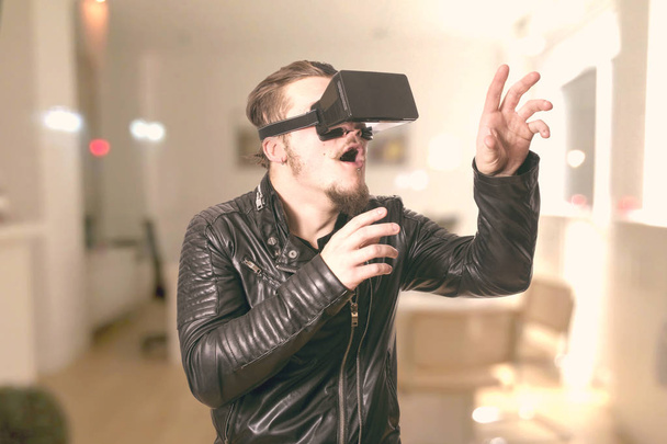 shocked man wearing VR glasses and playing in virtual reality simulation at home - Fotografie, Obrázek