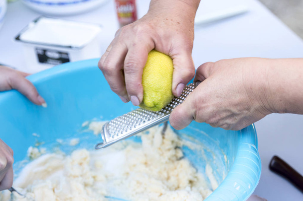 people preparing dough in blue washbowl and using Plane Grater with lemon, lemon zest - Foto, Imagen
