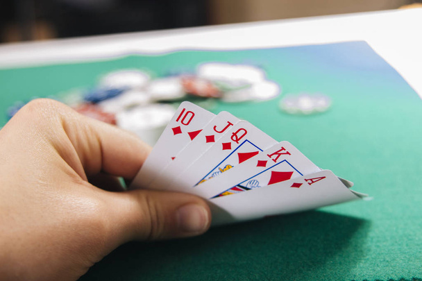 partial view of hand holding cards at green table casino - Fotografie, Obrázek