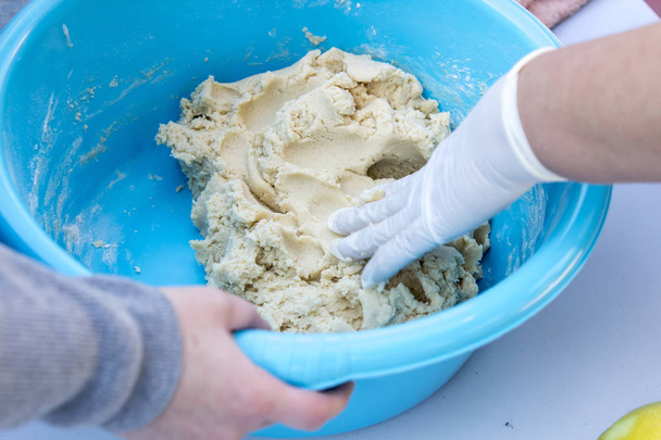 people hands preparing dough in blue washbowl - Foto, Imagen
