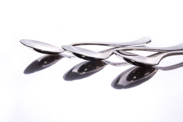 stainless steel spoons on glassy surface with reflection, studio shot - Foto, Imagem