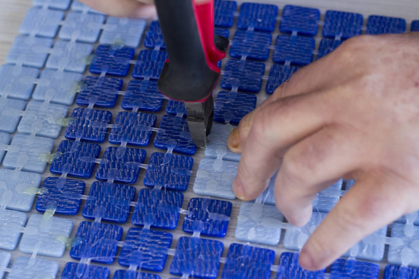 cropped image of person cutting blue mosaic tiles with pliers - Foto, afbeelding