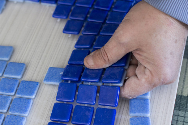 imagem cortada de pessoa segurando azulejos mosaico azul
 - Foto, Imagem
