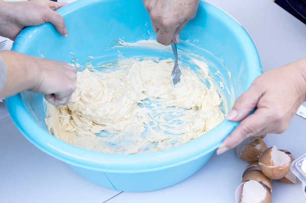 close up of people preparing dough in blue washbowl - Foto, afbeelding