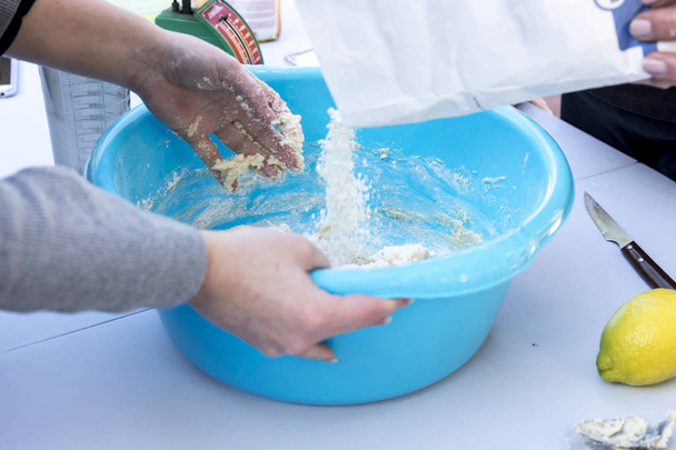 close up of person preparing dough in blue washbowl with flour package - Valokuva, kuva