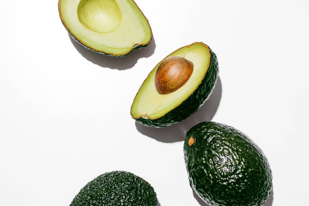 Beyaz bir arka plan üzerinde taze organik hass avokado, yaratıcı düz sağlıklı gıda kavramı yatıyordu. - Fotoğraf, Görsel