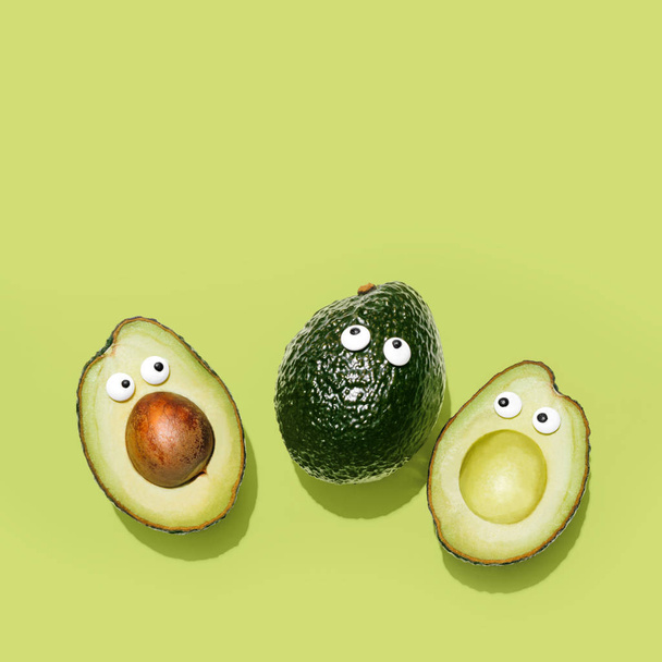 Funny faces avocados on a pastel green background, creative healthy food concept, top view with clipping path - Photo, Image