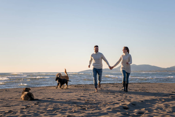 Couple Running On The Beach Holding Their Hands with dog On autmun day - Фото, зображення