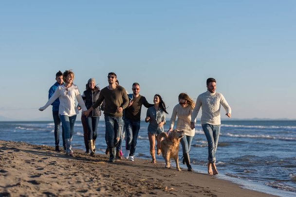 group of young friends spending day together running on the beach during autumn day - Zdjęcie, obraz