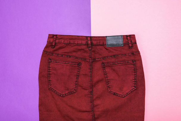 Бордовий джинсового спідниця на два кольори фону. Модні джинсові жіночого одягу. Джинсовий жіночого одягу на кольоровому фоні. - Фото, зображення