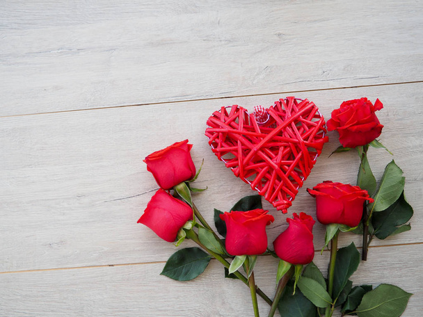 木製のテーブル、上面に赤いバラ、ハートのロマンチックな背景 - 写真・画像