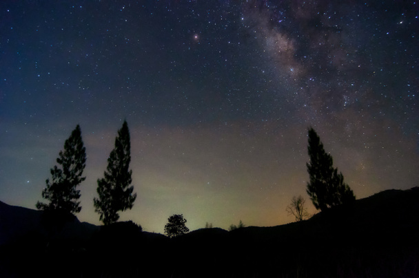 Vía Láctea galaxia con estrellas y polvo espacial en el universo y la luz del zodíaco en el cielo nocturno sobre el pino en el paisaje de montaña con movimiento de nubes, Phu Sawan embalse Phetchaburi
. - Foto, imagen