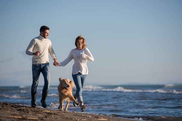 Couple Running On The Beach Holding Their Hands with dog On autmun day - Foto, Imagem