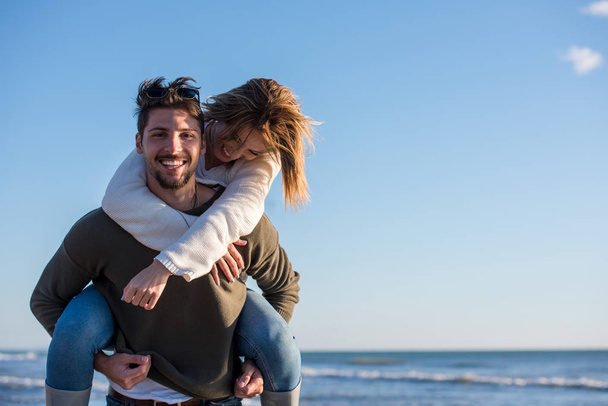 Men Giving Piggy Back Rides to his girlfriend At Sunset By The Sea, autumn time - 写真・画像