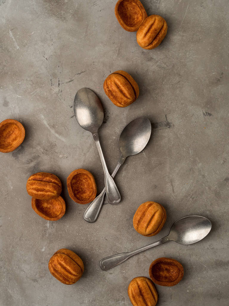 Vintage silver spoons with brown cookies on grey concrete background - Fotó, kép