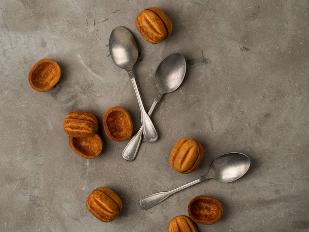 Vintage silver spoons with brown cookies walnuts shape on grey concrete background - Fotó, kép
