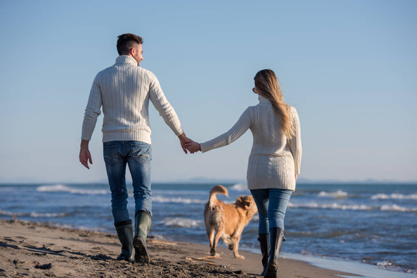 犬と手をつないでビーチを走るカップル秋の日 - 写真・画像