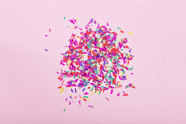 Minimalismus. Parteihintergrund. Festlich gefärbtes Konfetti auf rosa Hintergrund. Ansicht von oben. Kopierraum. Grußkarte. Hoppeliger Geburtstag - Foto, Bild