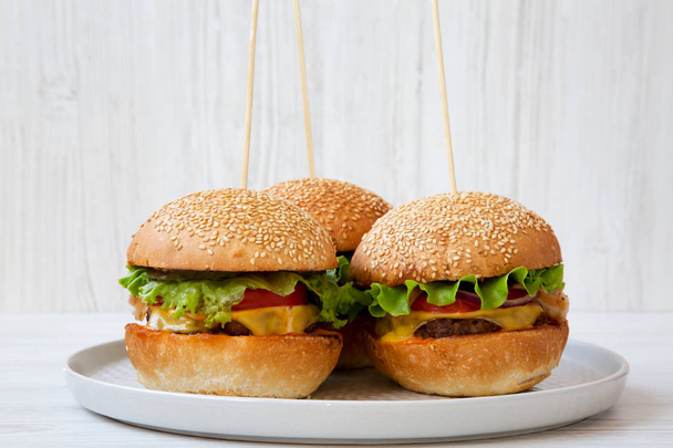 Cheeseburgers on grey plate on white wooden background. Side view. Close-up. - Fotoğraf, Görsel