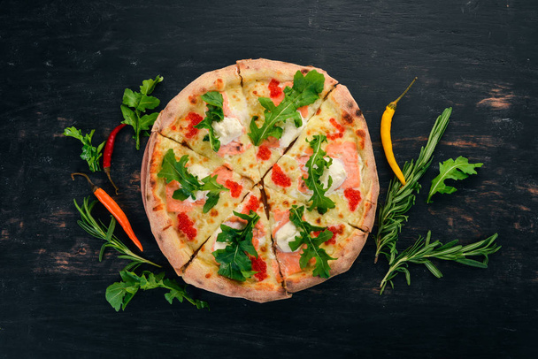 Pizza with salmon and caviar. Seafood. Italian cuisine. On a wooden background. Free space for text. Top view. - Photo, Image