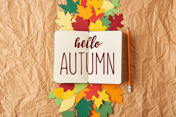 disposición plana con "hola otoño" inspiración en cuaderno, lápiz y hojas de papel artesanal de colores sobre fondo de papel arrugado
 - Foto, Imagen