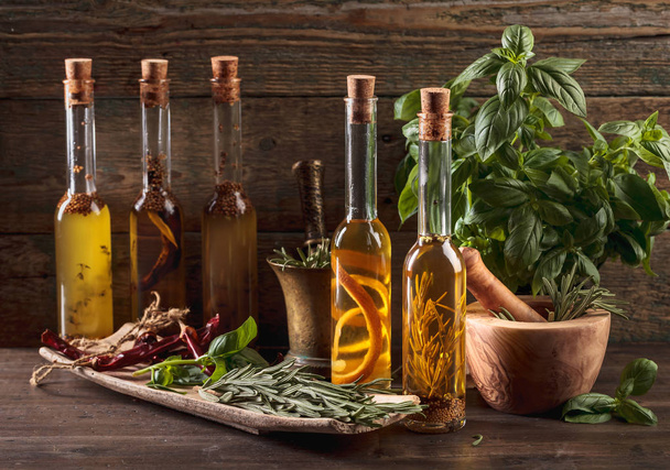 Az olívaolaj különböző fűszerek és gyógynövények egy régi fából készült asztal. - Fotó, kép