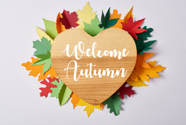 top view of wooden heart shaped board and colorful handcrafted leaves on white surface with "welcome autumn" lettering - Photo, Image