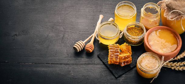 A set of honey and bee products. Honey in honeycomb. On a black wooden background. Free space for text. Top view. - Photo, image