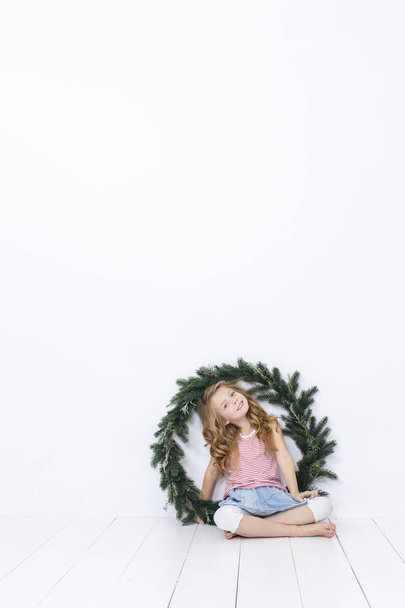 Happy beautiful girl posing with christmas wreath isolated on white background - Фото, изображение