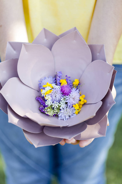 female hands holding beautiful purple floral bowl with flowers at meadow  - Φωτογραφία, εικόνα
