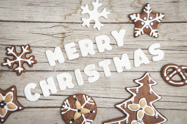 Frohe Weihnachten Schriftzug mit Lebkuchen auf Holztischplatte - Foto, Bild