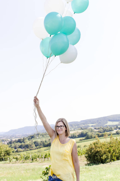 Happy woman with balloons having fun on meadow at summer sunny day  - Foto, Bild