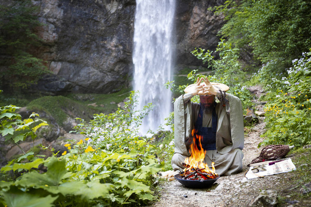 Hombre europeo con barba y bata japonesa haciendo una ceremonia de fuego frente a la Gran Cascada en Austria
 - Foto, imagen